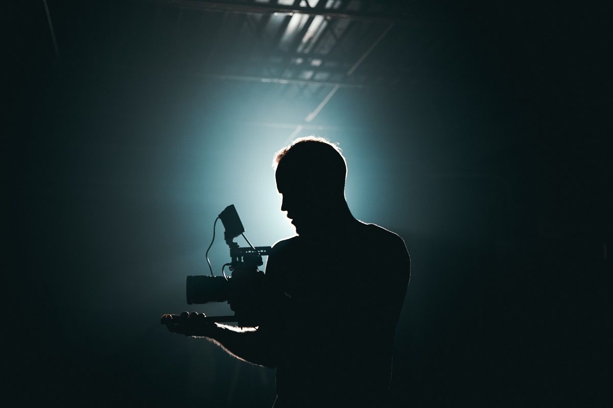silhouette of video creator holding camera in darkroom