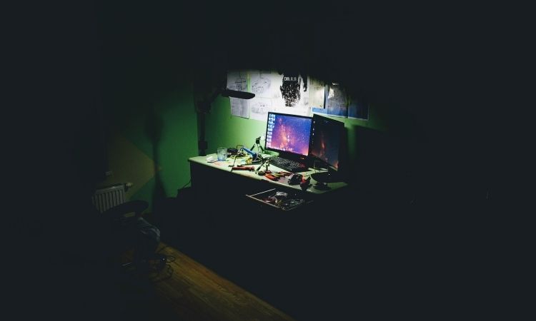 dark room with green walls lit by computer with tools around it