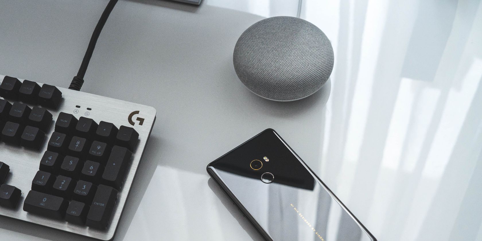 google home, keyboard, and phone on office desk