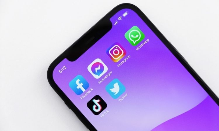 black iPhone with purple wallpaper and social media apps