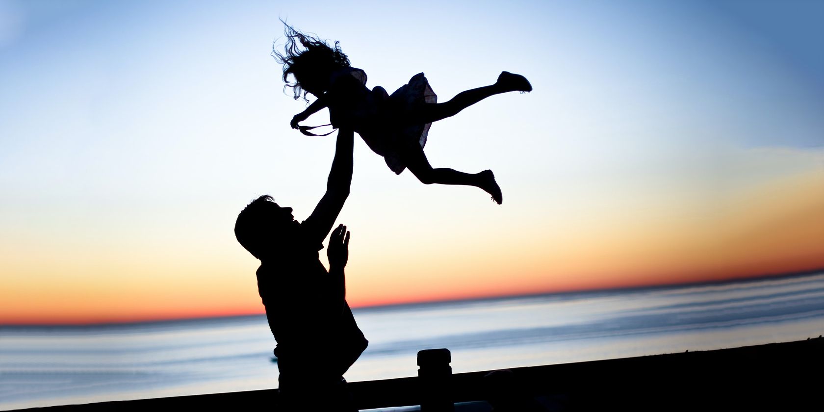 man playing with his young daughter on a beach