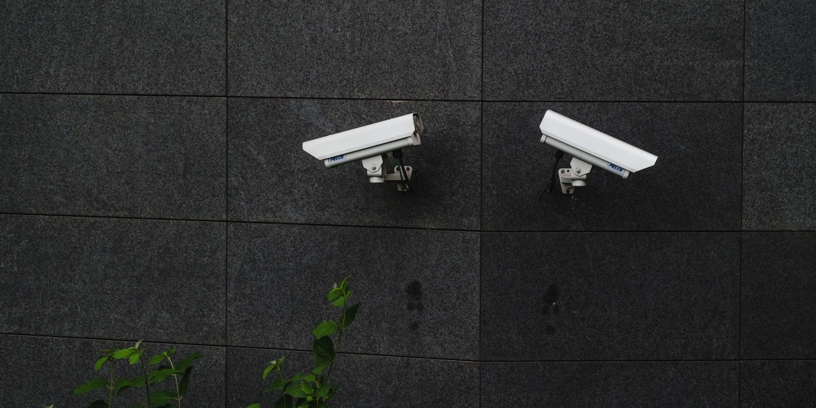 two white security cameras on the side of a building