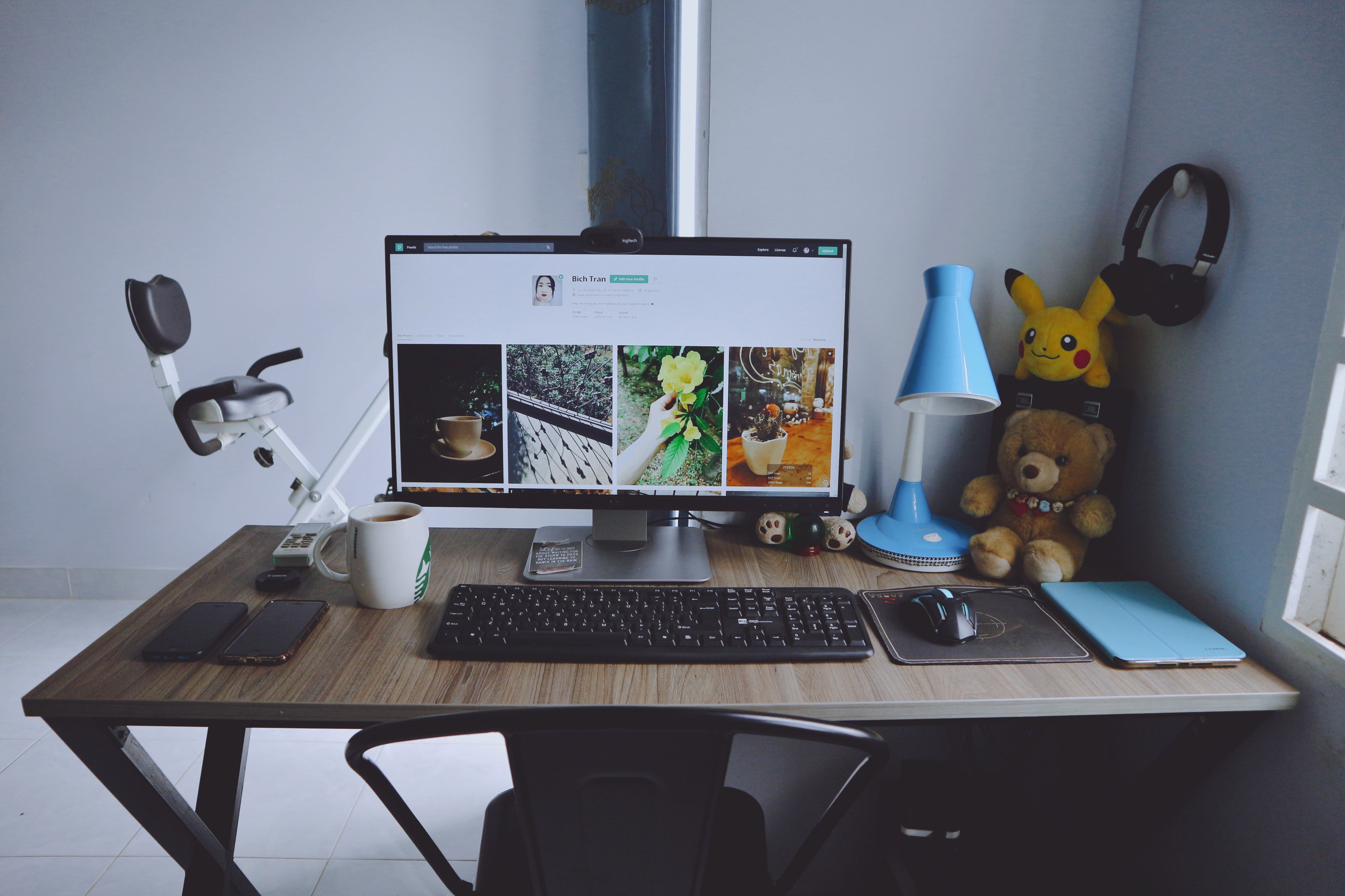 A neat workspace at home with a desktop, a coffee mug, a table lamp, and other stuff 