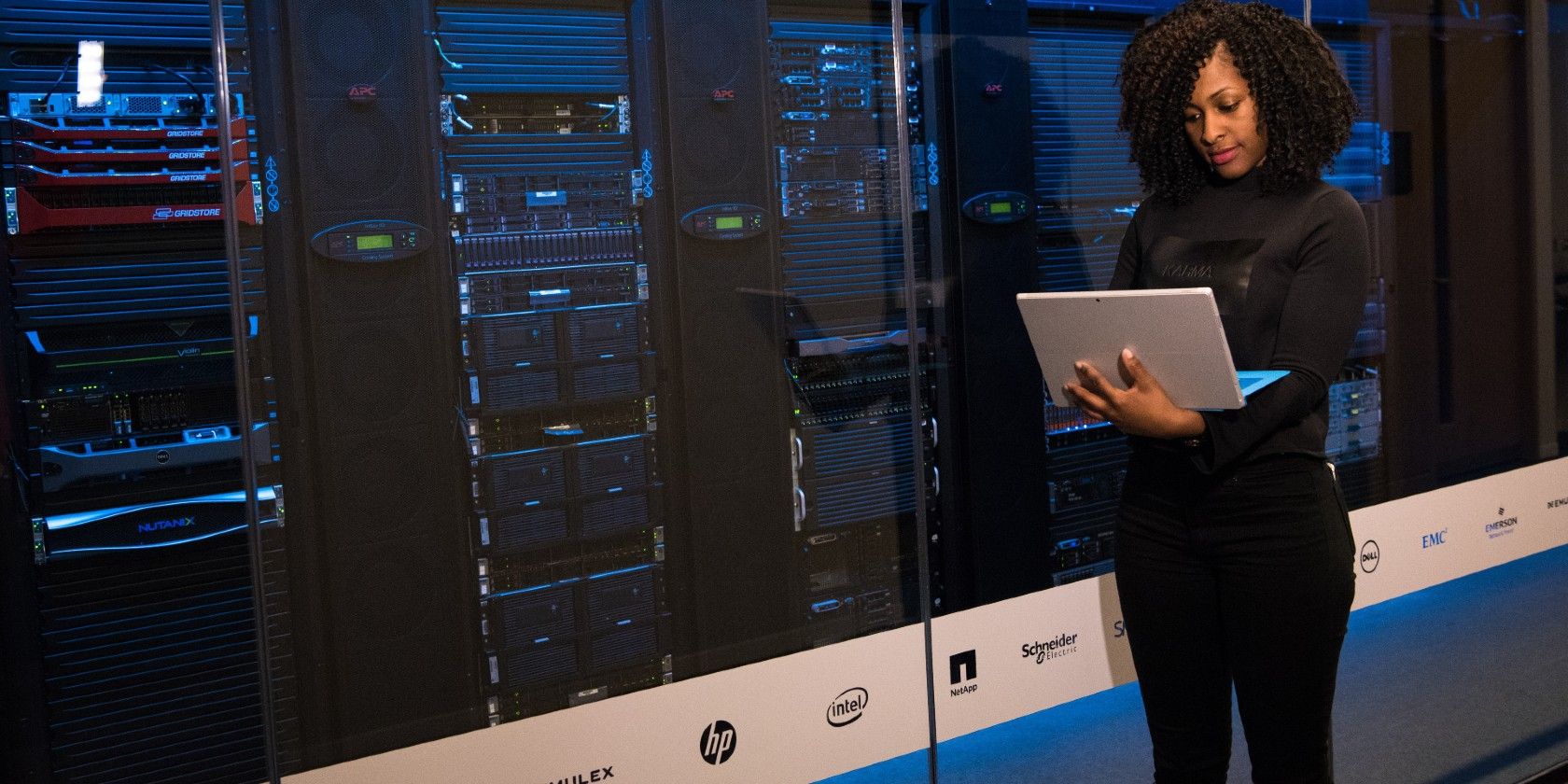 Woman holding a laptop in front of a server