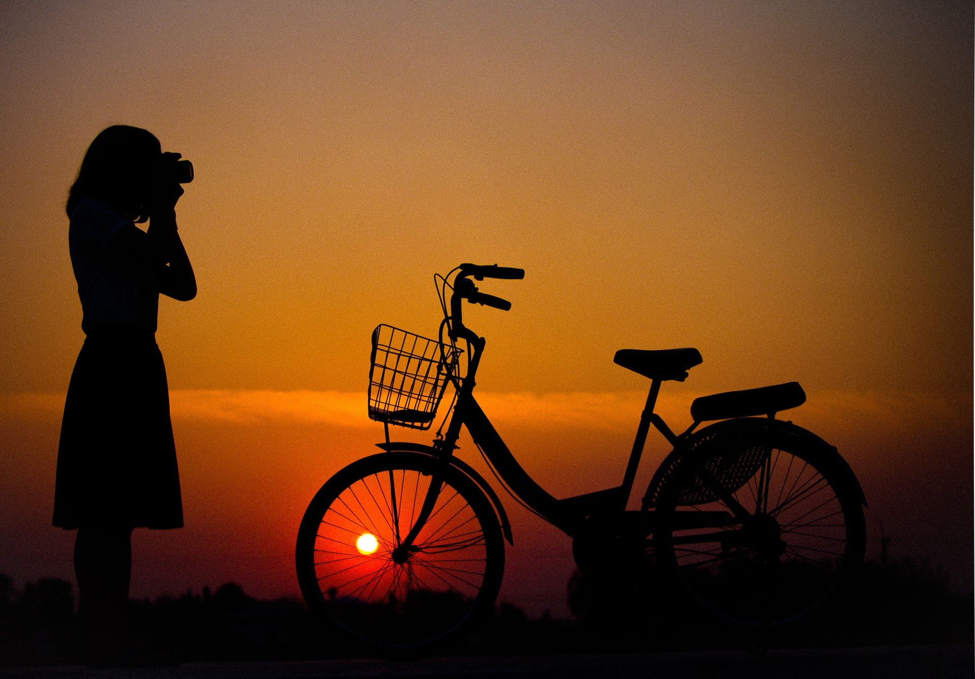 A girl photographing a bike at sunset
