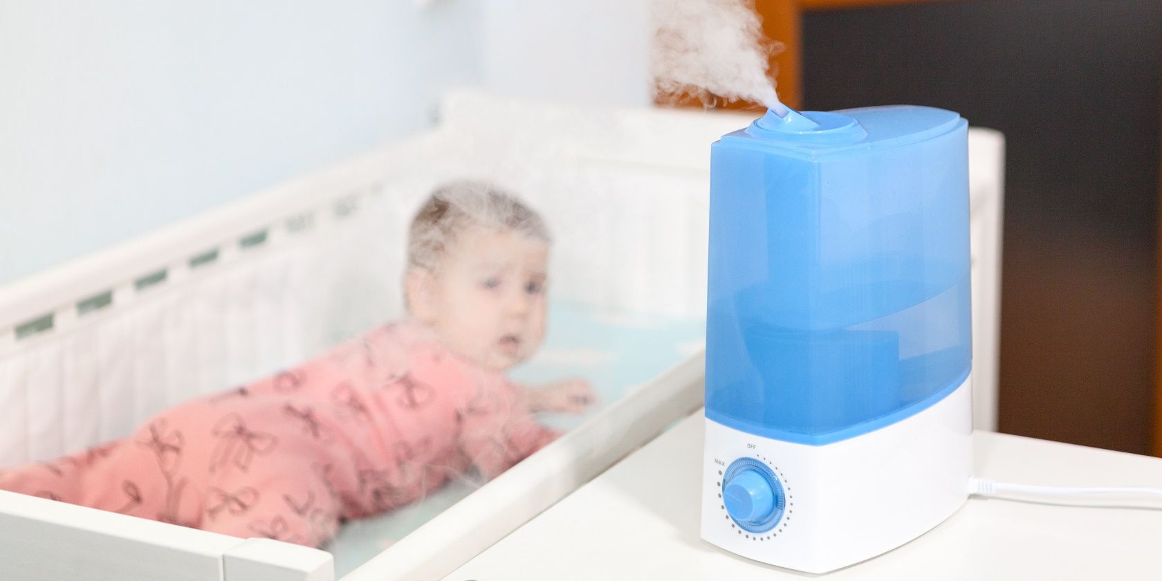 Using humidifier at home, blue ultrasonic device working on table in nursery room