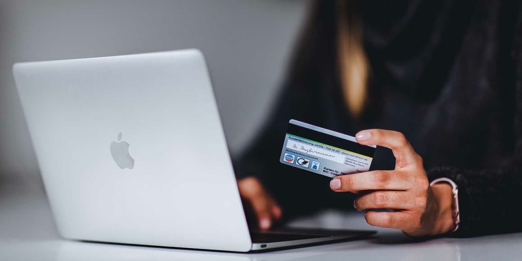 woman shopping on MacBook holding credit card