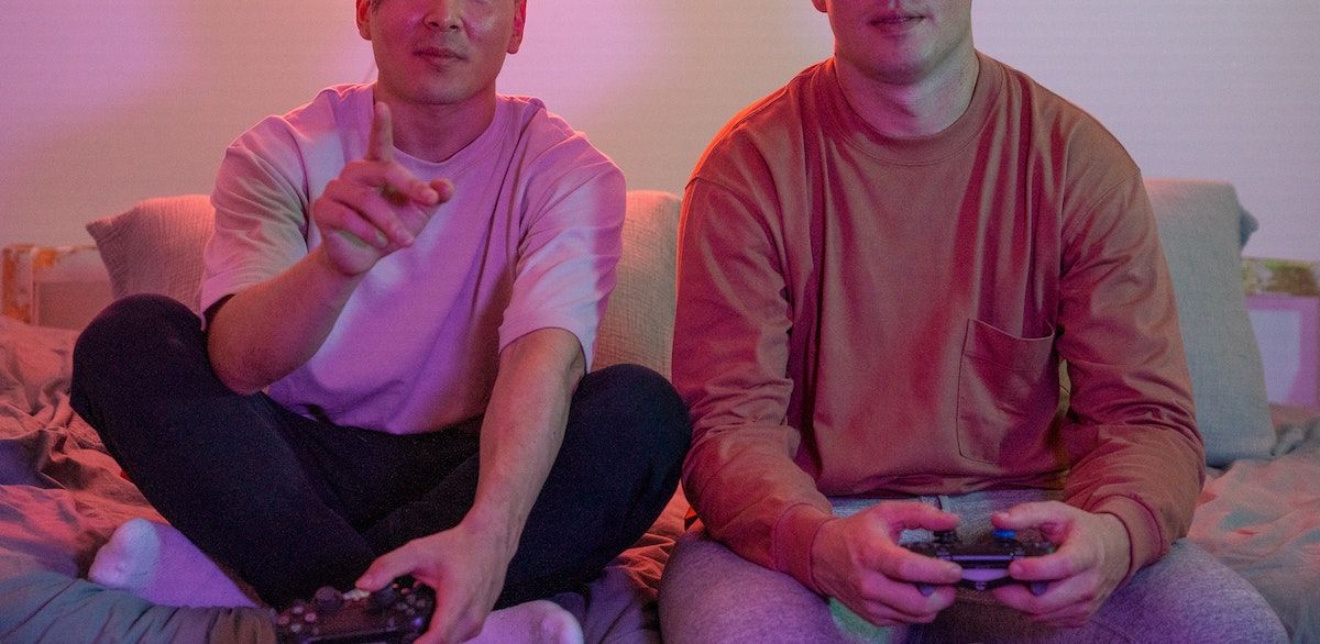 two people playing video games holding PS4 controllers