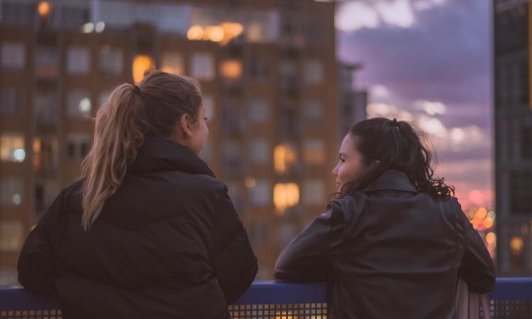 Two women were standing by a railing overlooking a city.