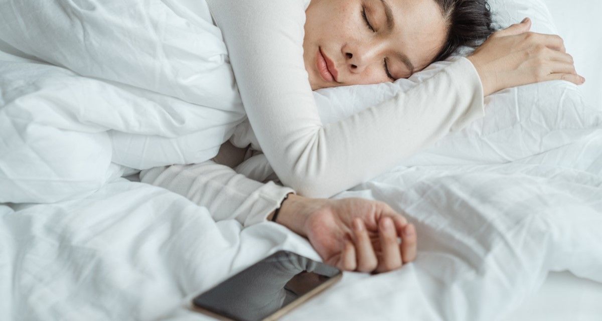 sleeping woman with phone on the bed