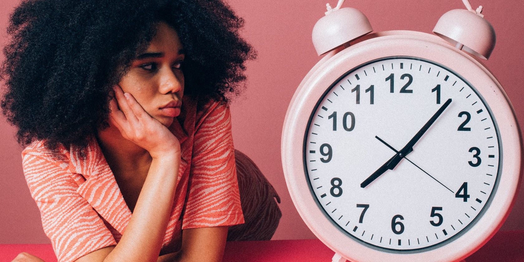 A woman sitting beside a big alarm clock