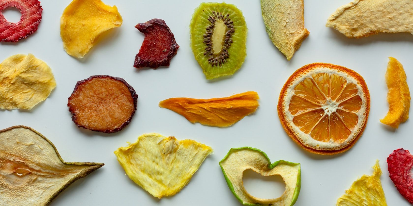 A mix of freeze dried fruits laid flat on a grey background
