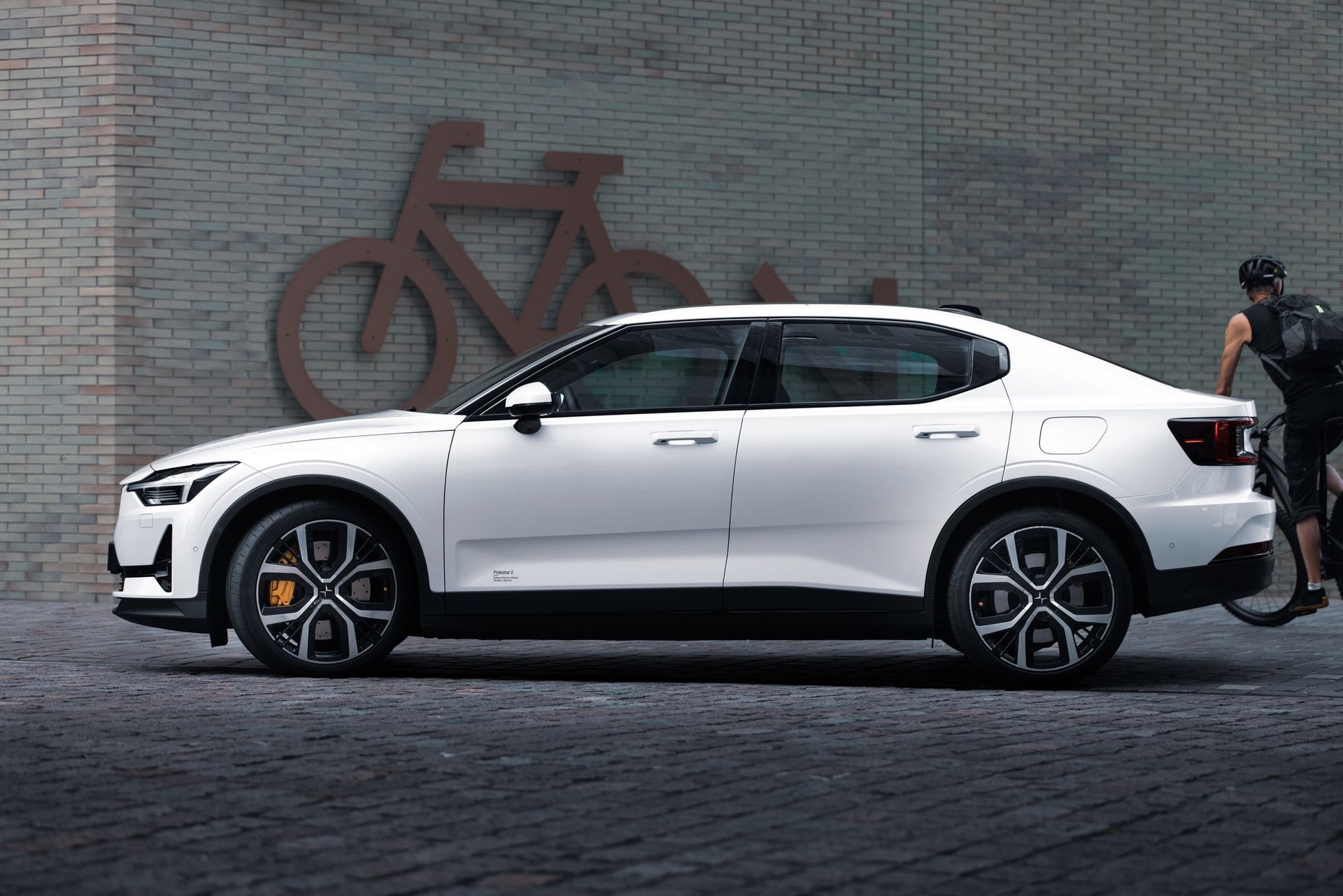 White Polestar 2 fully electric vehicle on the street against brick wall