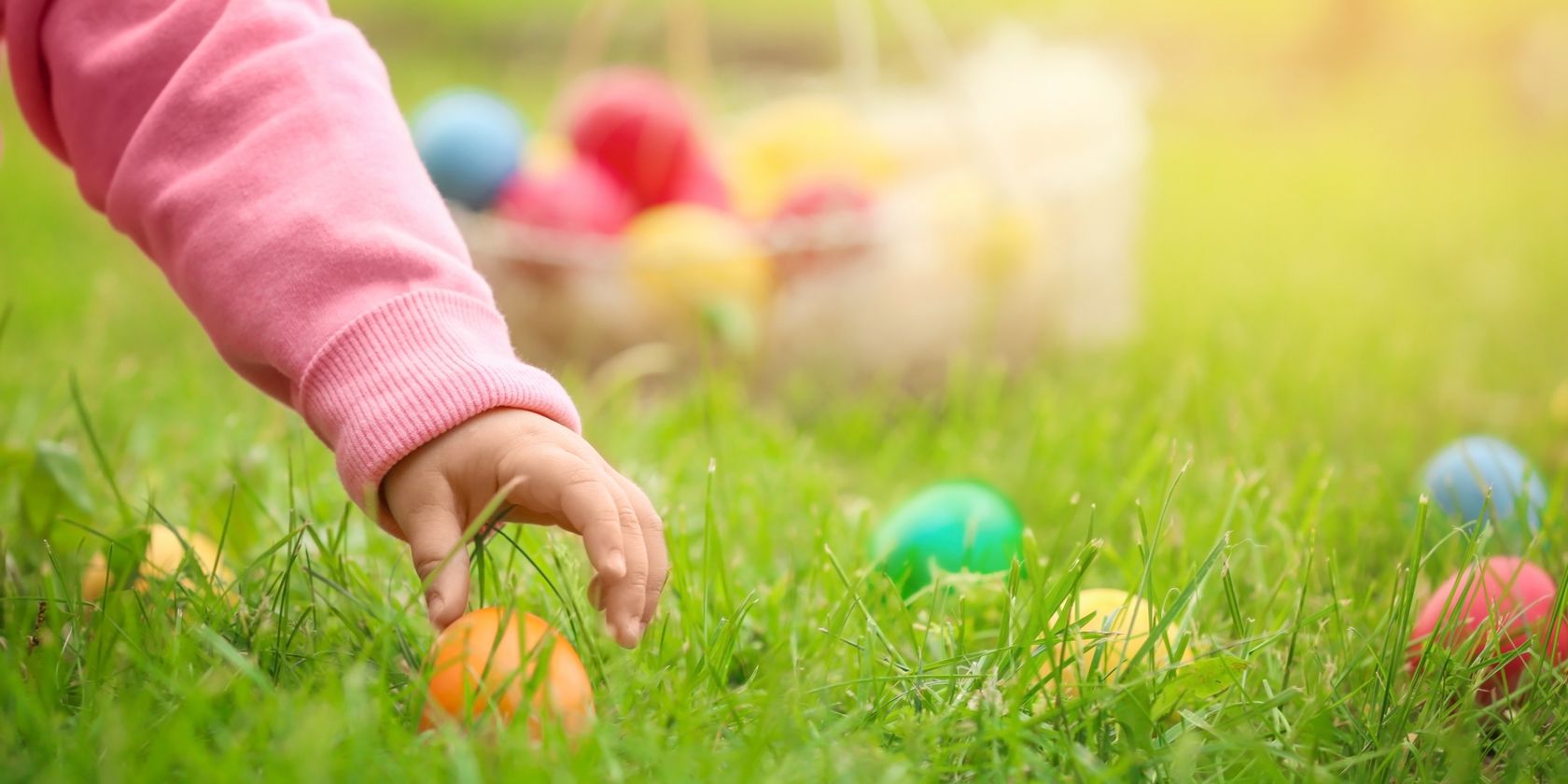 Child's hand picking up Easter egg in the grass