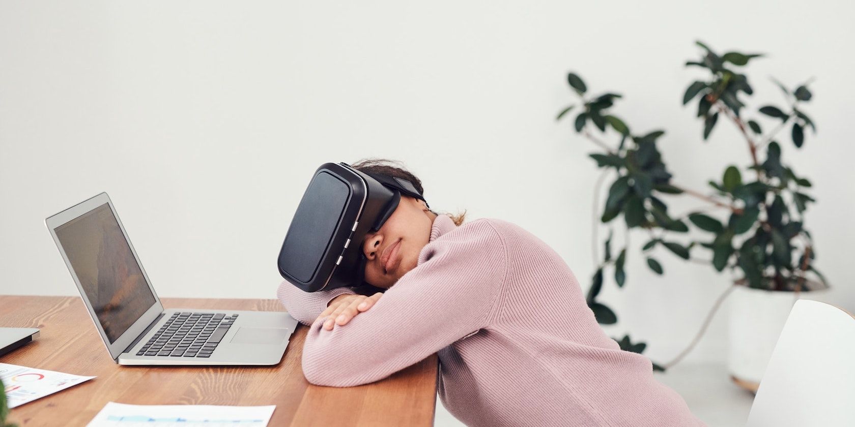 A woman leaning on a work desk while wearing a VR headset