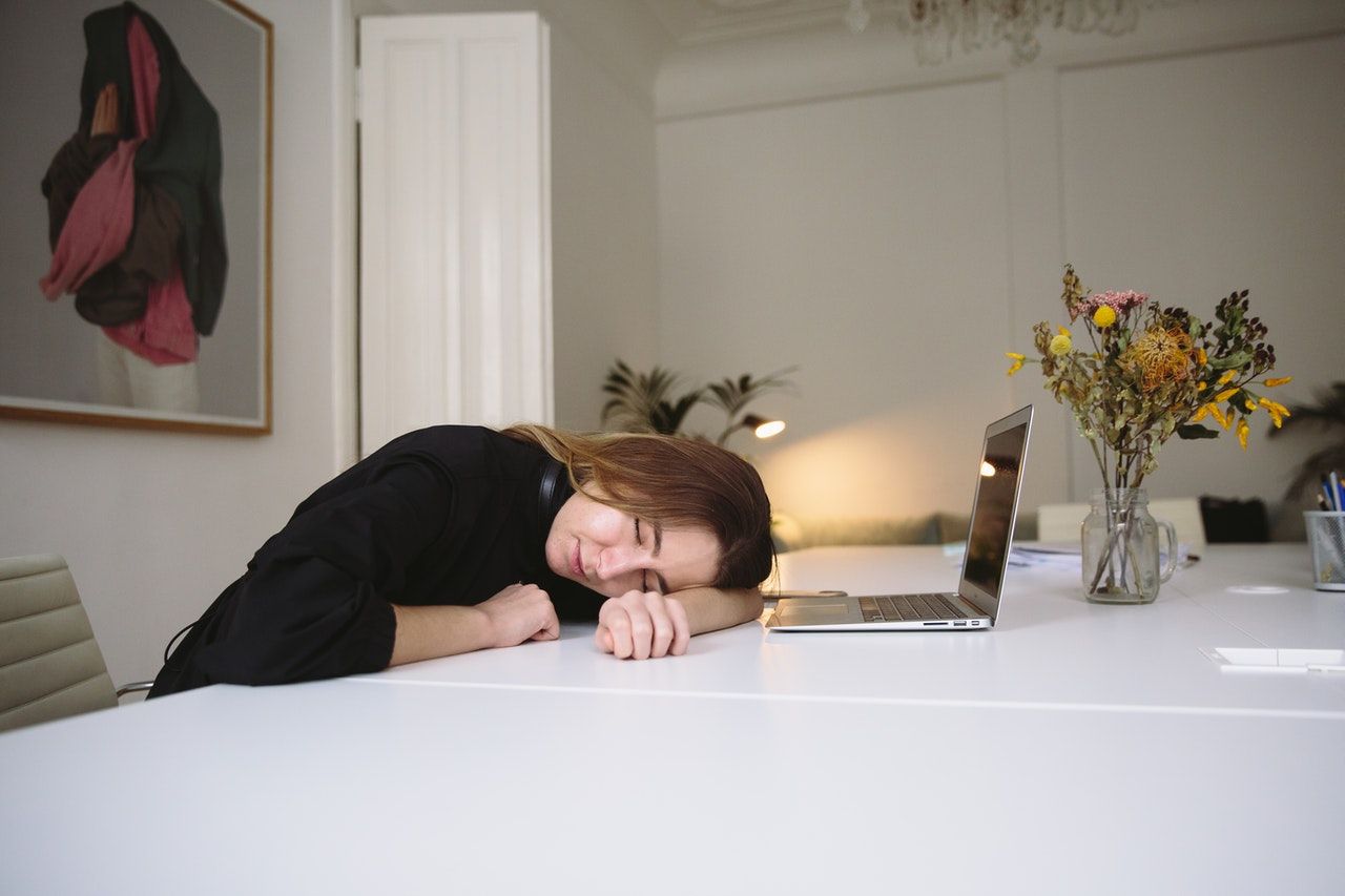 Woman Sleeping on Table with Laptop in Sleep Mode