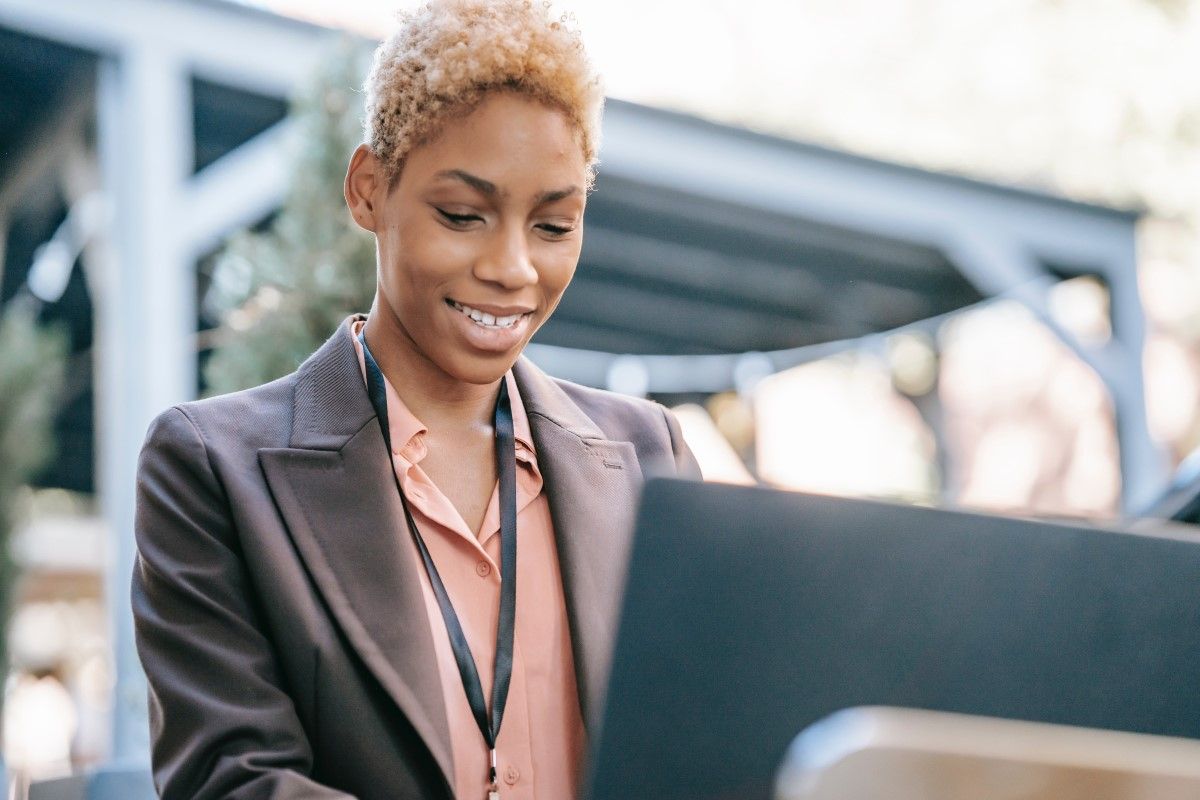 Black woman in a business suit standing and working on a computer