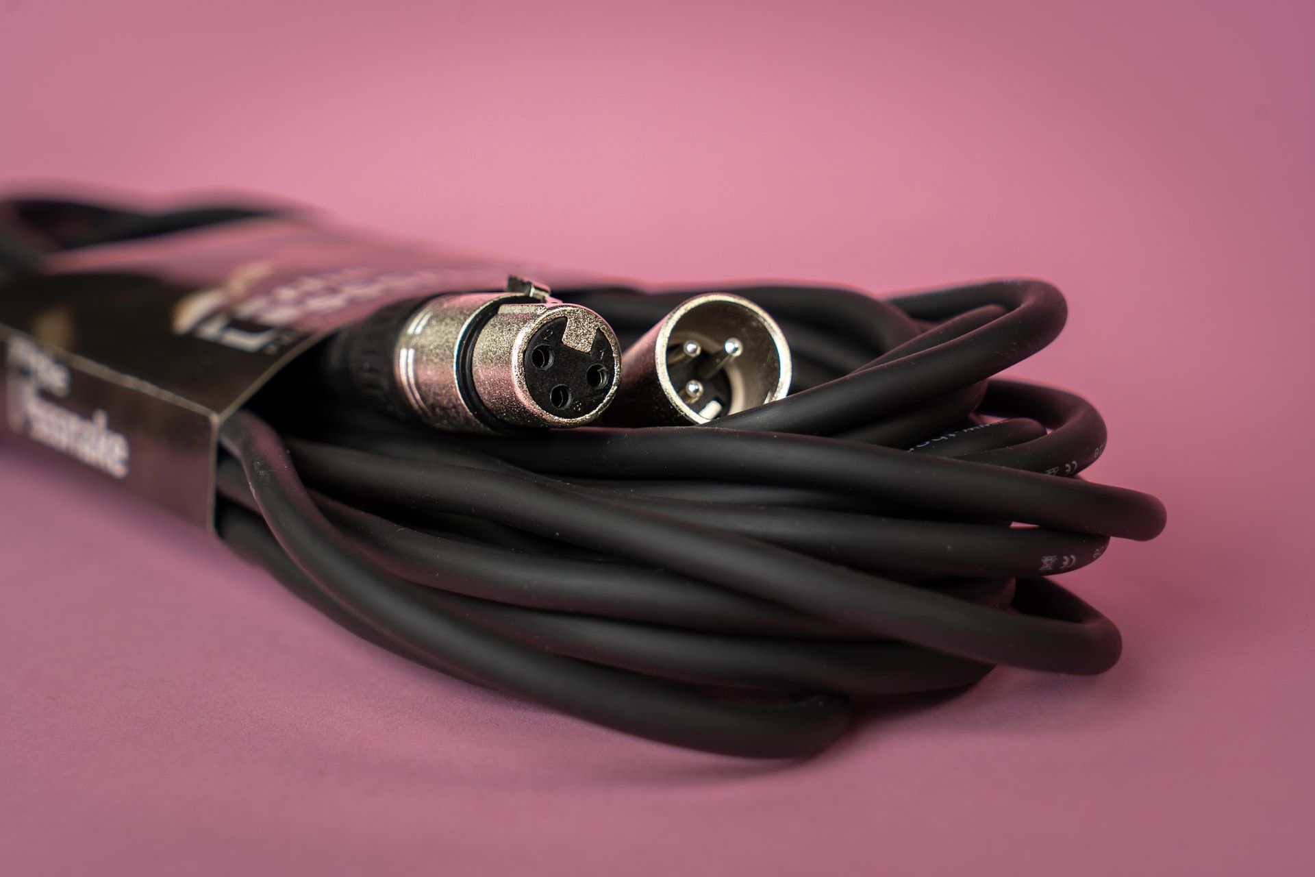 A close up shot of an XLR cable on a pink background