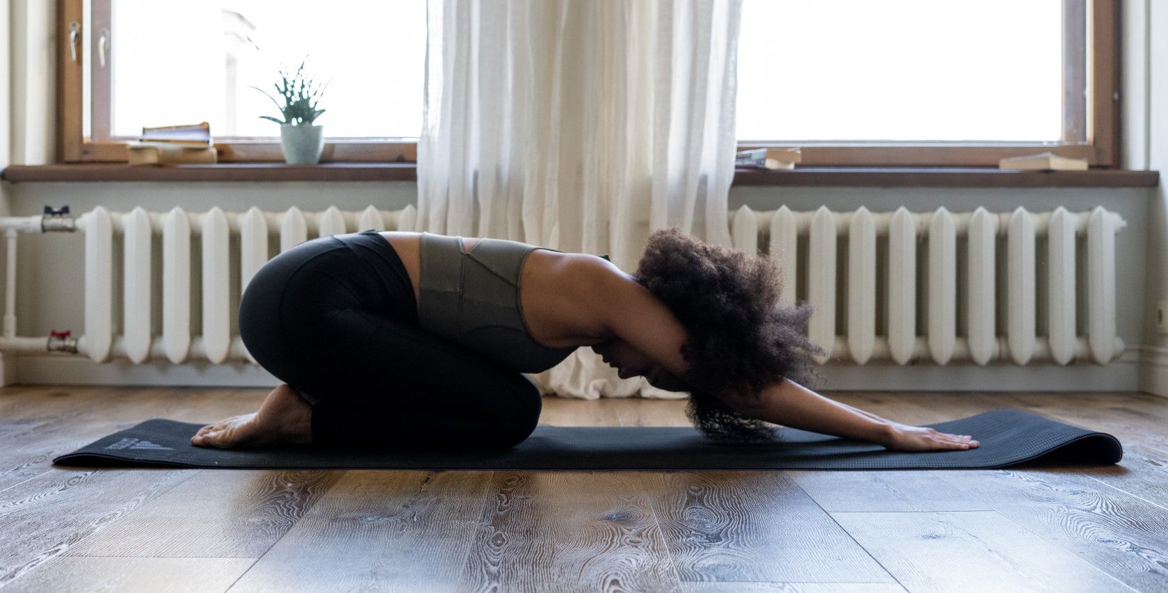 woman indoors performing yoga pose on yoga mat