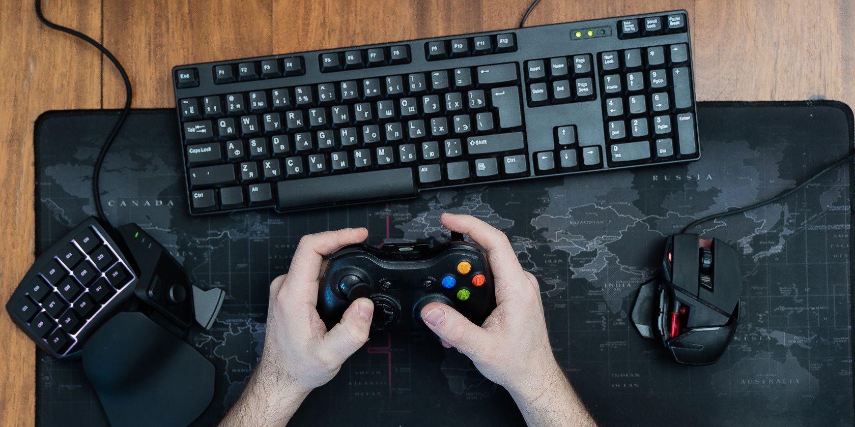 a man holds a game pad around a gaming keyboard in his hands, a game pad mouse. top view