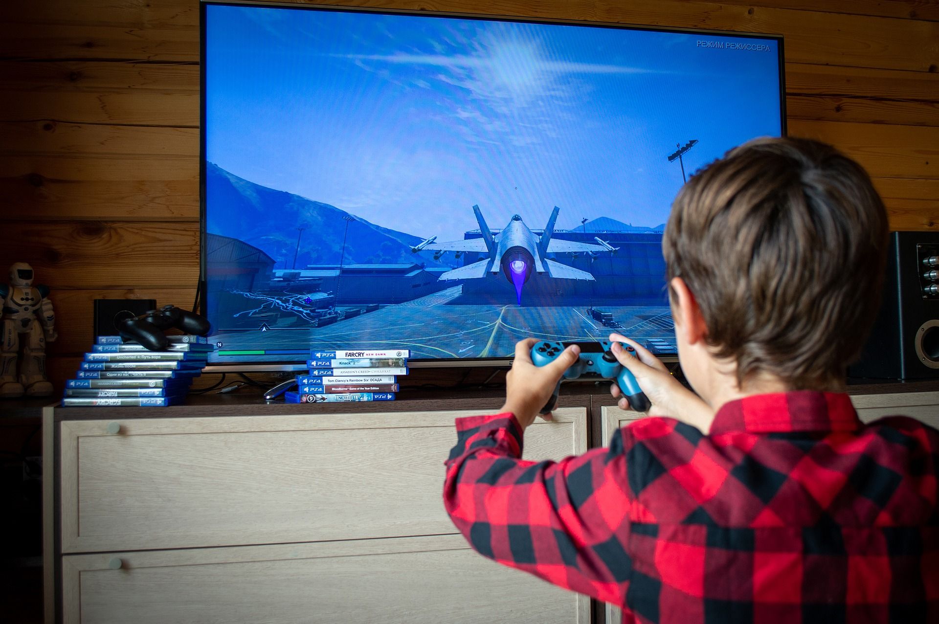 boy playing videogames on playstation 4 with ps4 game cases in background