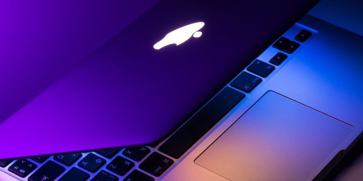 Closeup of a macbook with lid half folded over in a purple light