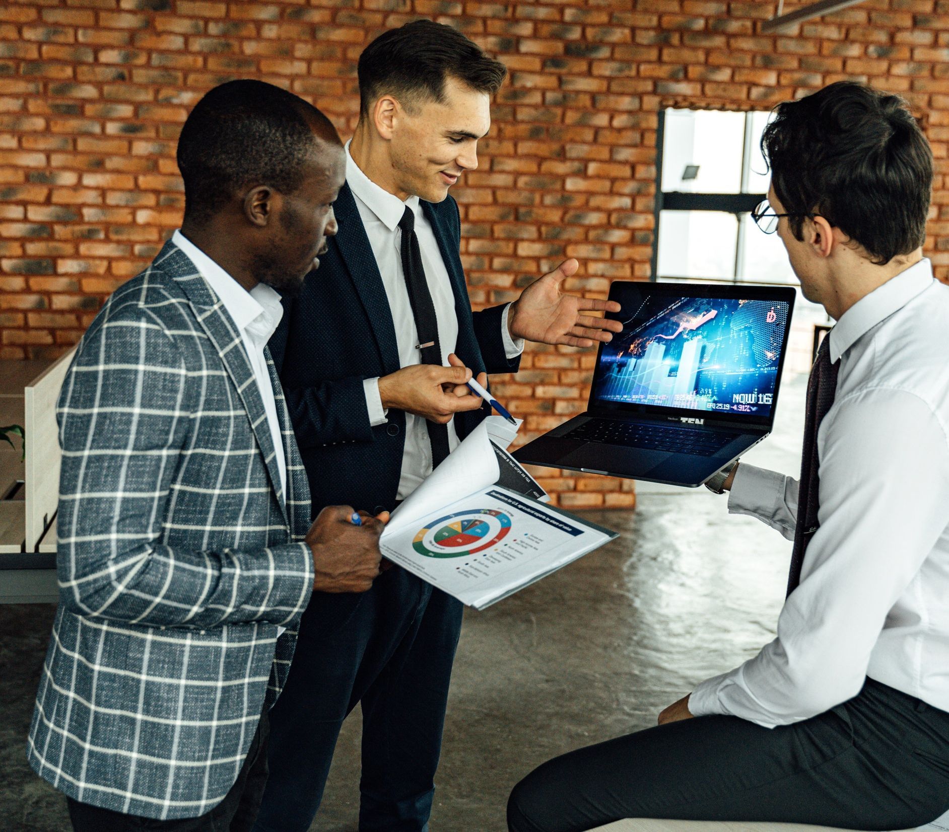 three men in the office discussing presentation next to each other