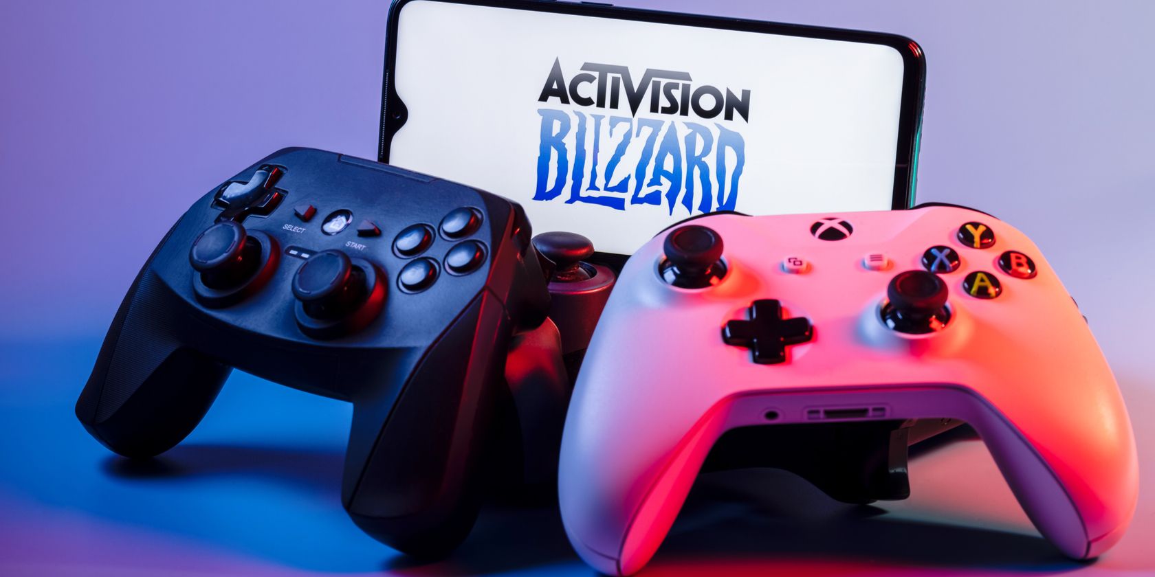 Two controllers next to a phone displaying Activision Blizzard's logo