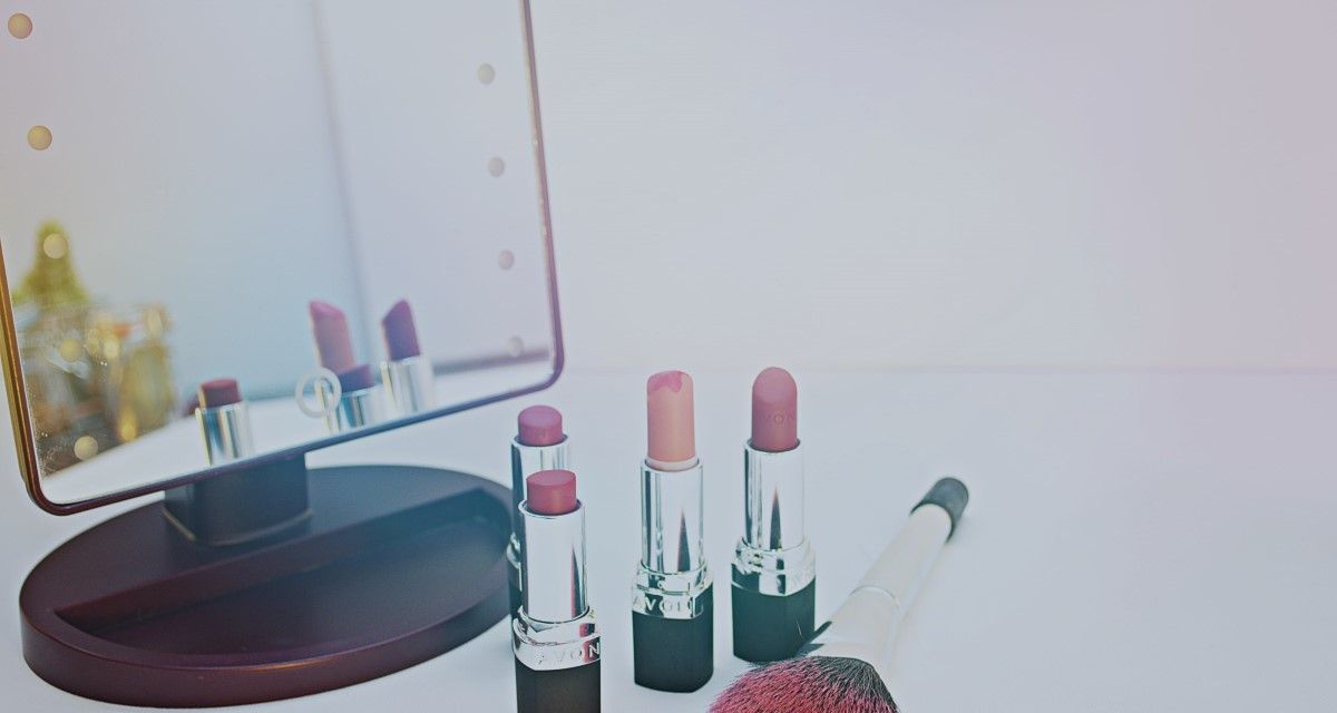 mirror with four lipsticks and a makeup brush