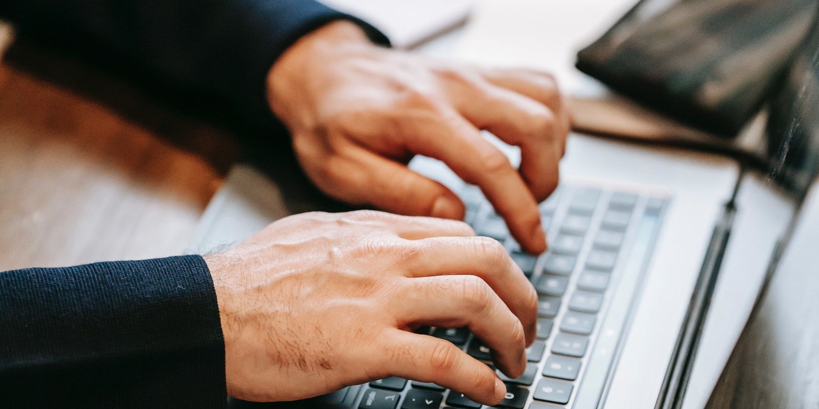 Image of two hands typing on a laptop