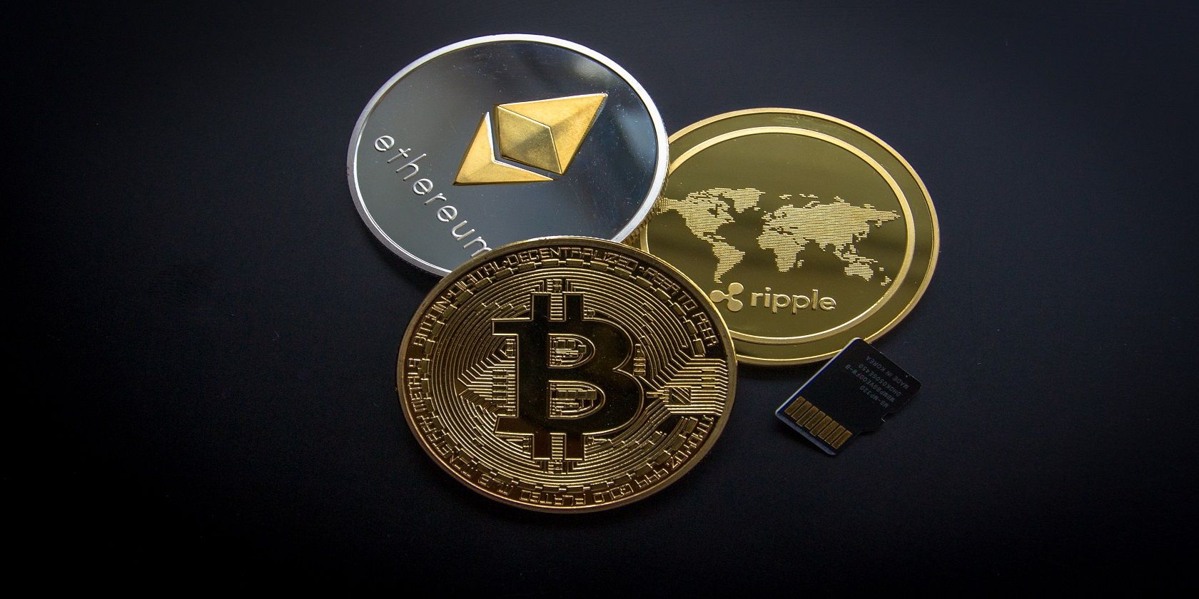 physical bitcoin, ethereum, and ripple coins next to a sim card