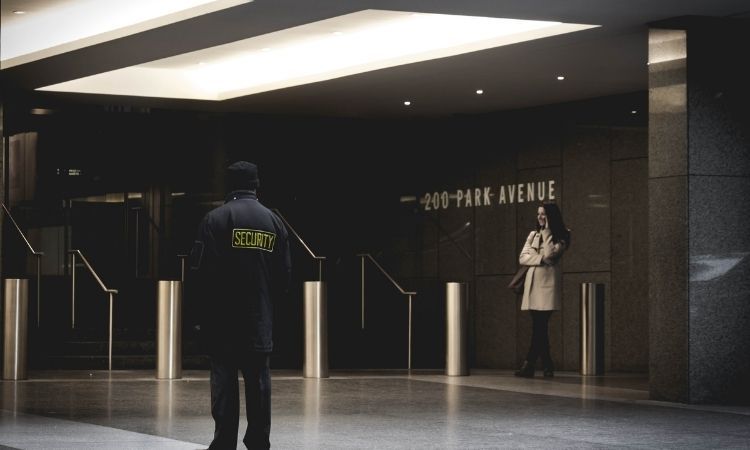 security guard at entrance of a building with a woman on her phone
