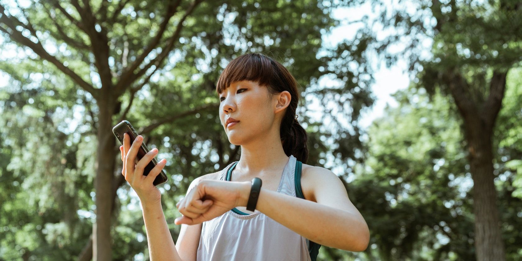 Sportswoman using smartphone and fitness tracker