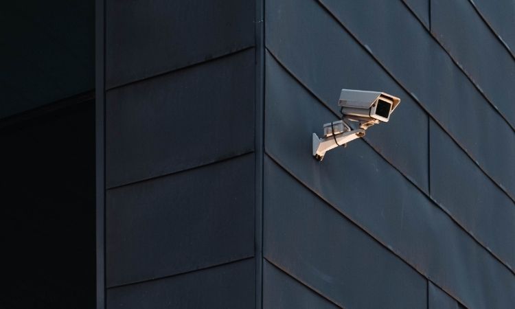 white surveillance camera on the siding of a black building