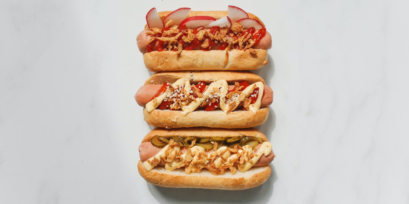 three gourmet hotdogs with different toppings and sauces