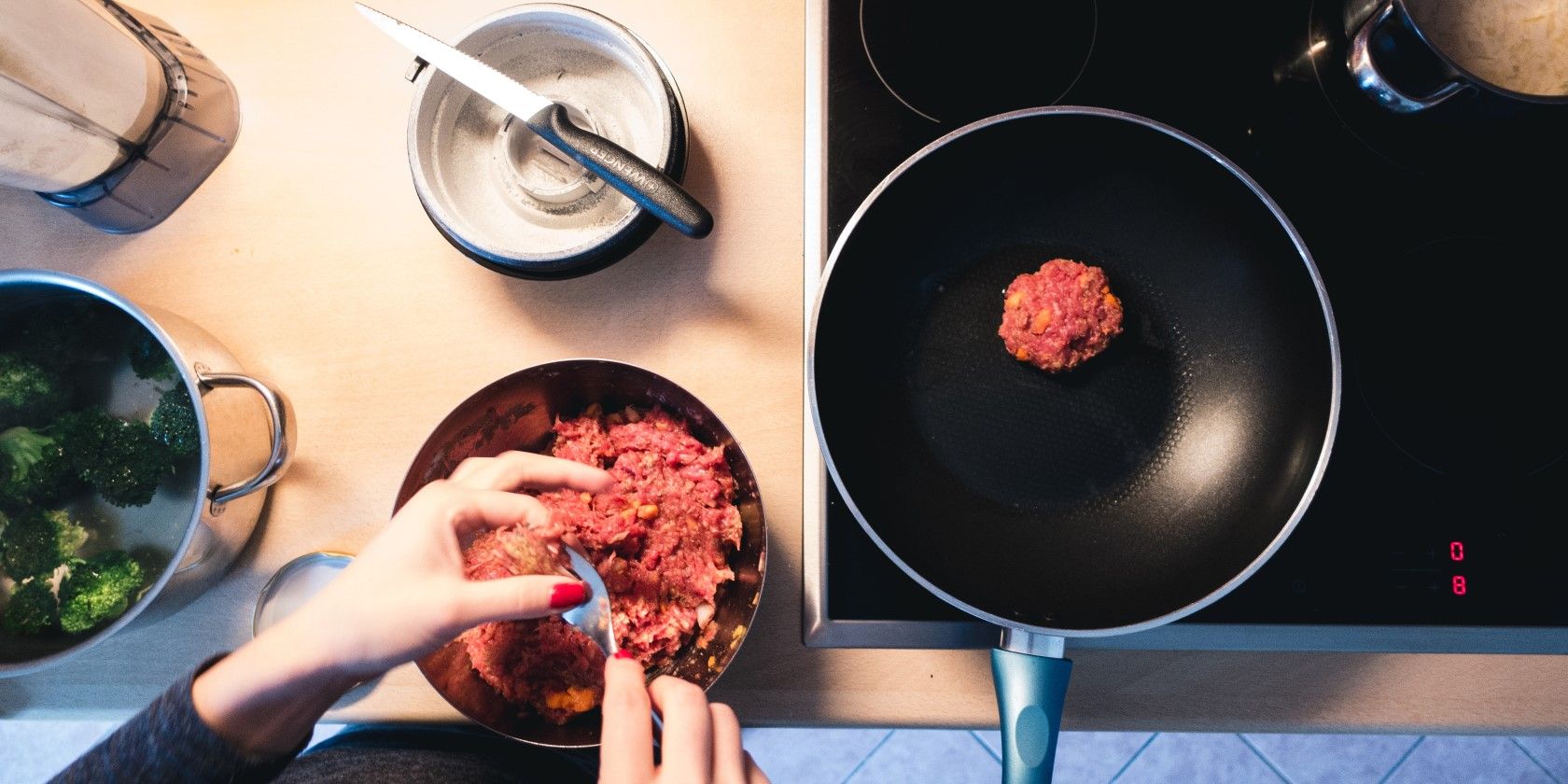 hands frying meat in a pan