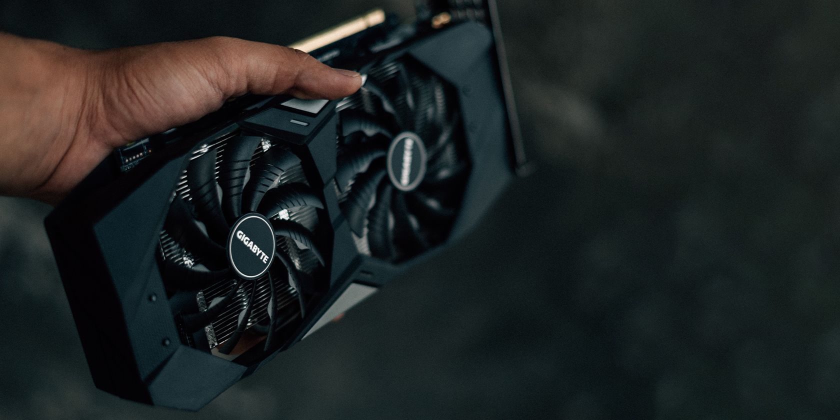 a hand holding a video card with two big fans