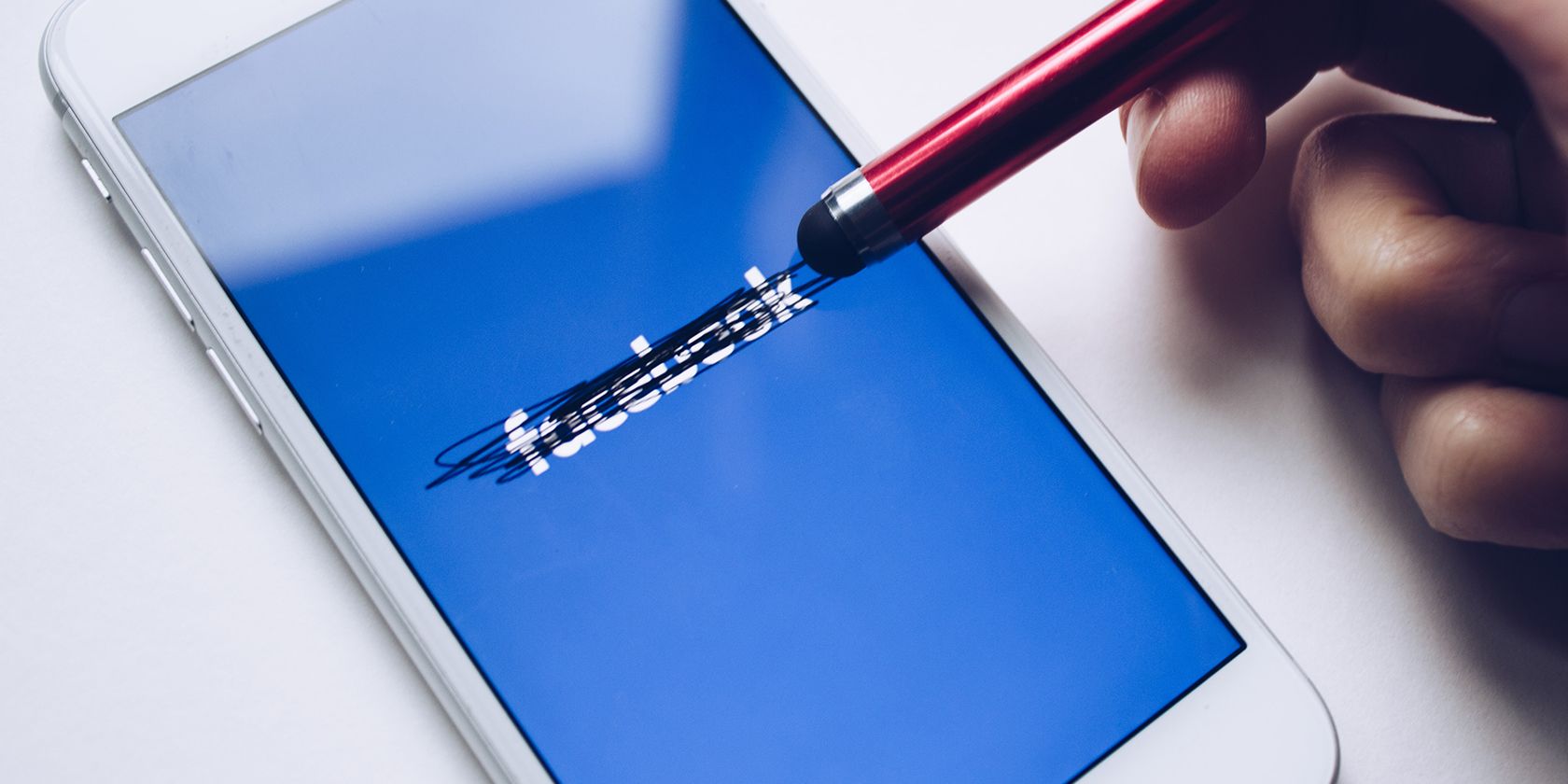 A person crossing out the Facebook logo with a stylus.