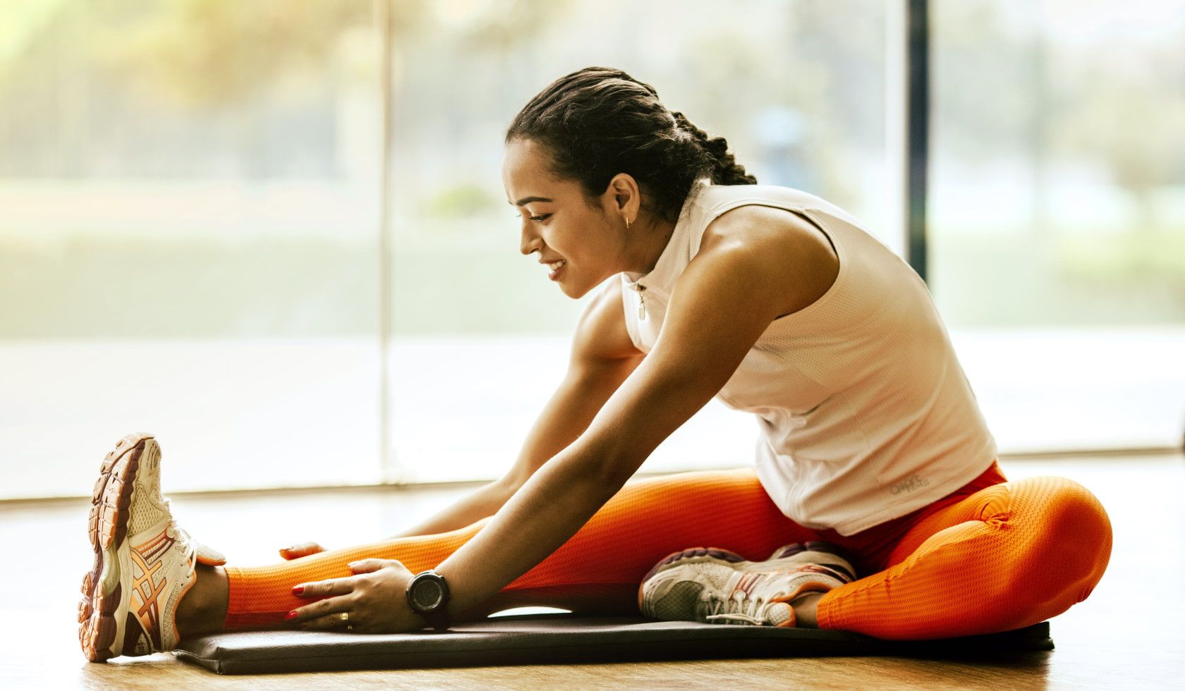 woman stretching while sitting on exercise mat