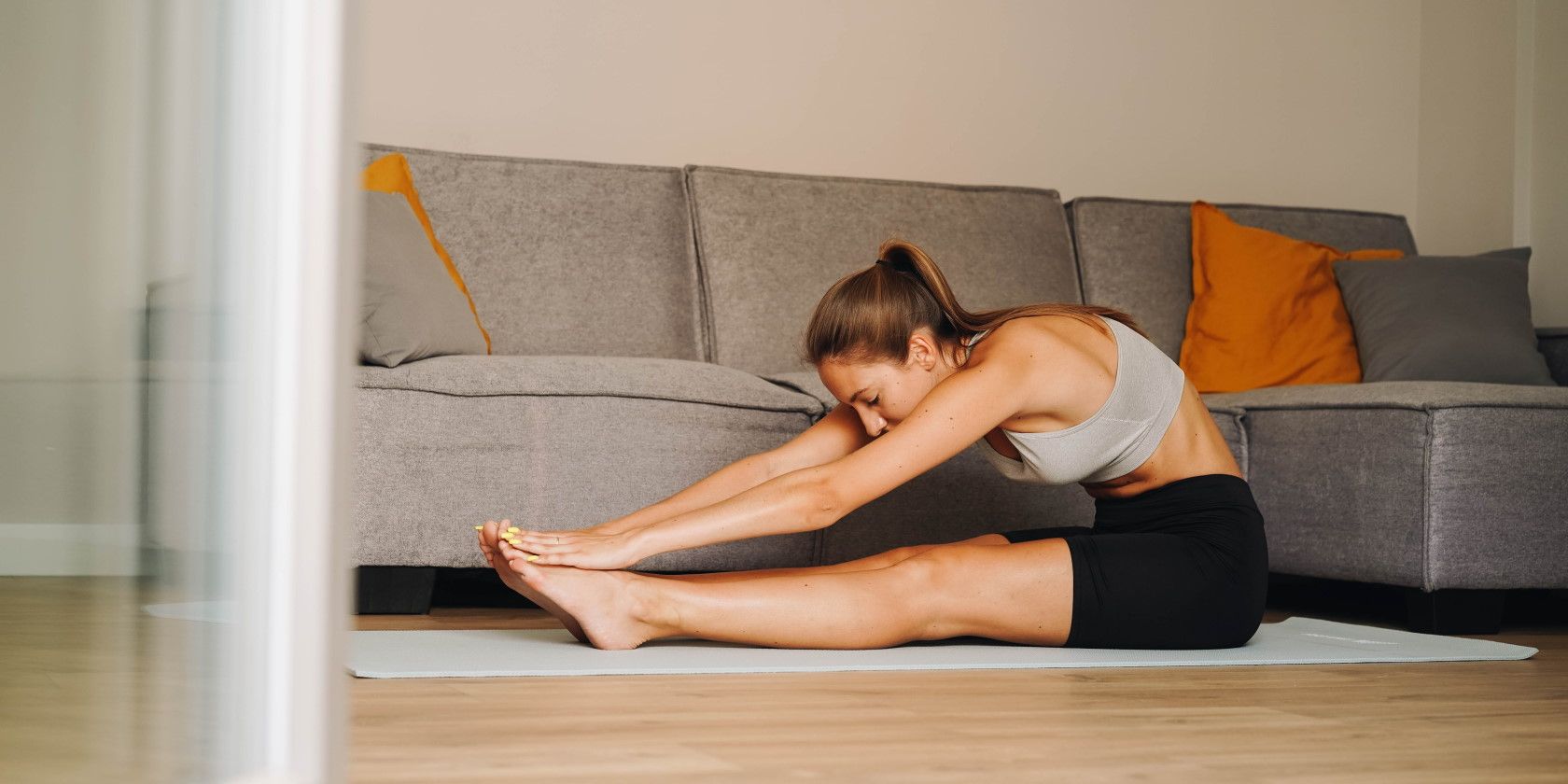 woman sitting on floor stretching on yoga mat