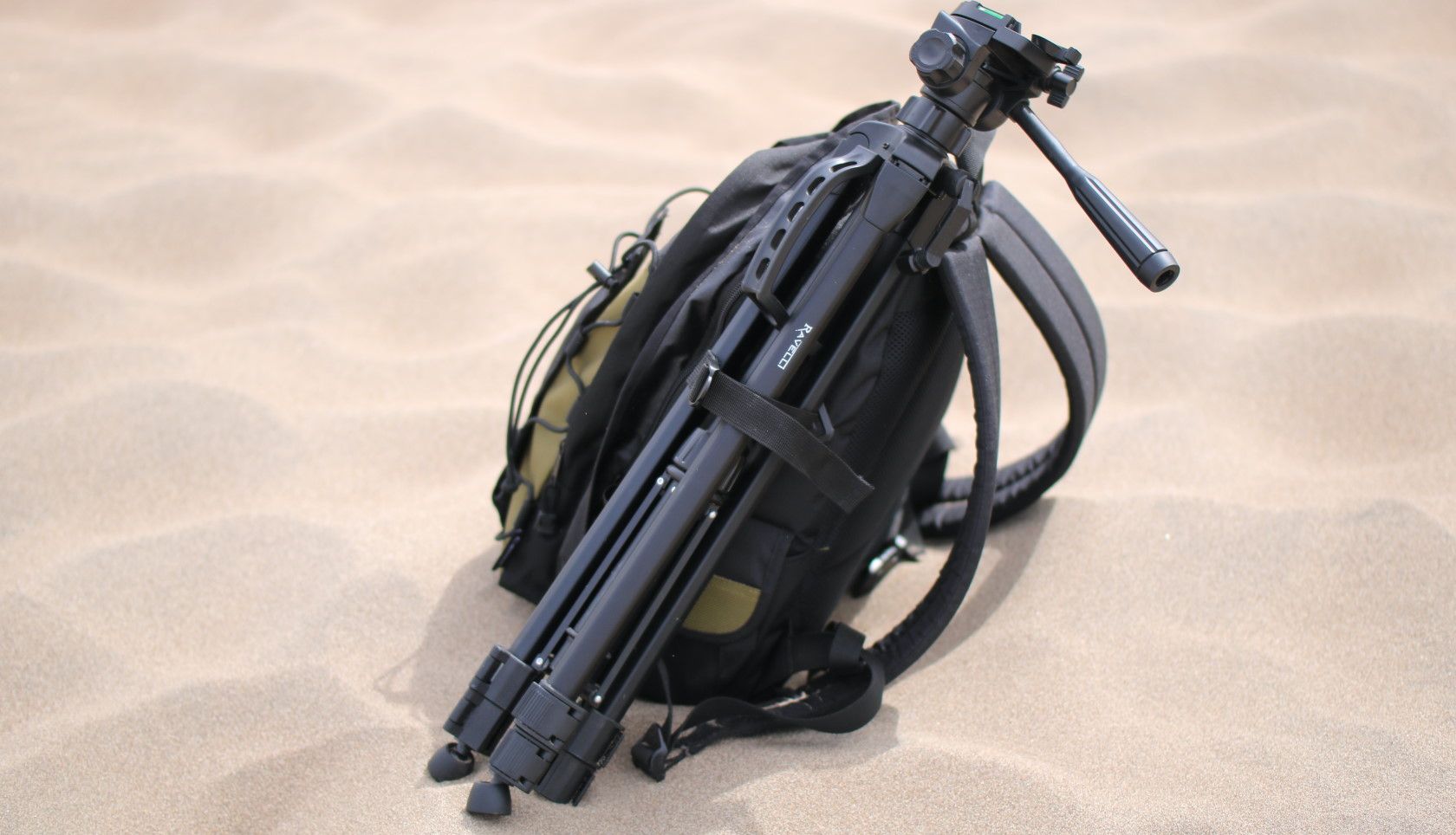Camera bag on desert sand attached to camera tripod
