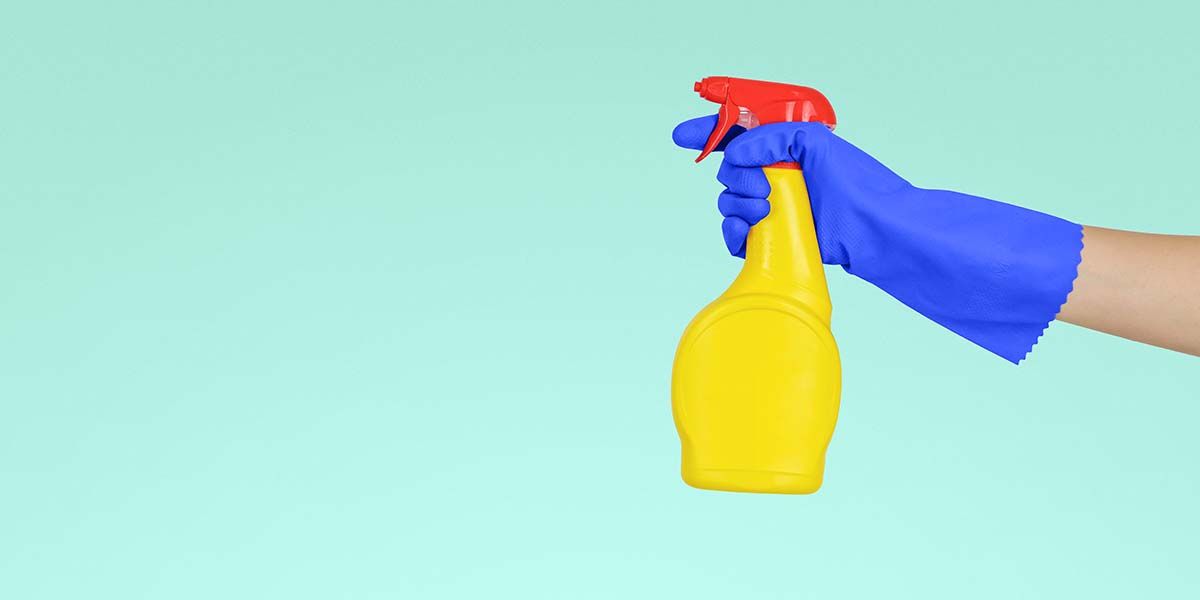 Photo of a spray bottle being held in edited blue rubber gloves.