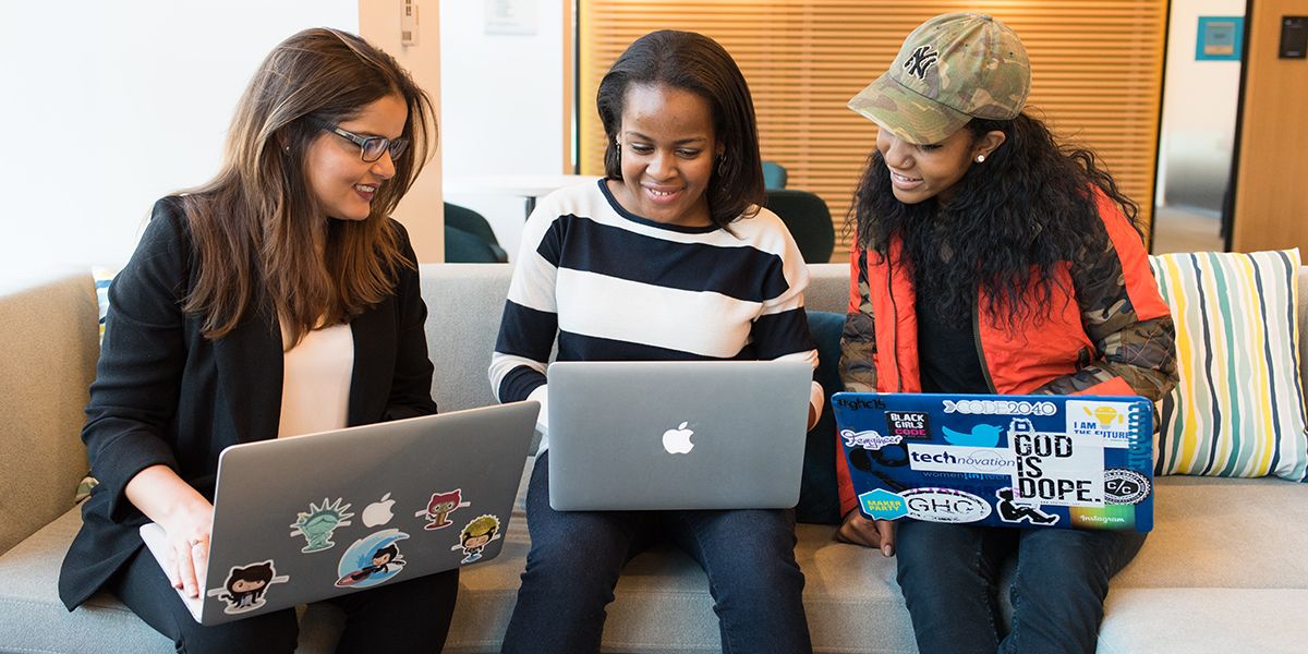 A photo of three women all looking at their three laptops