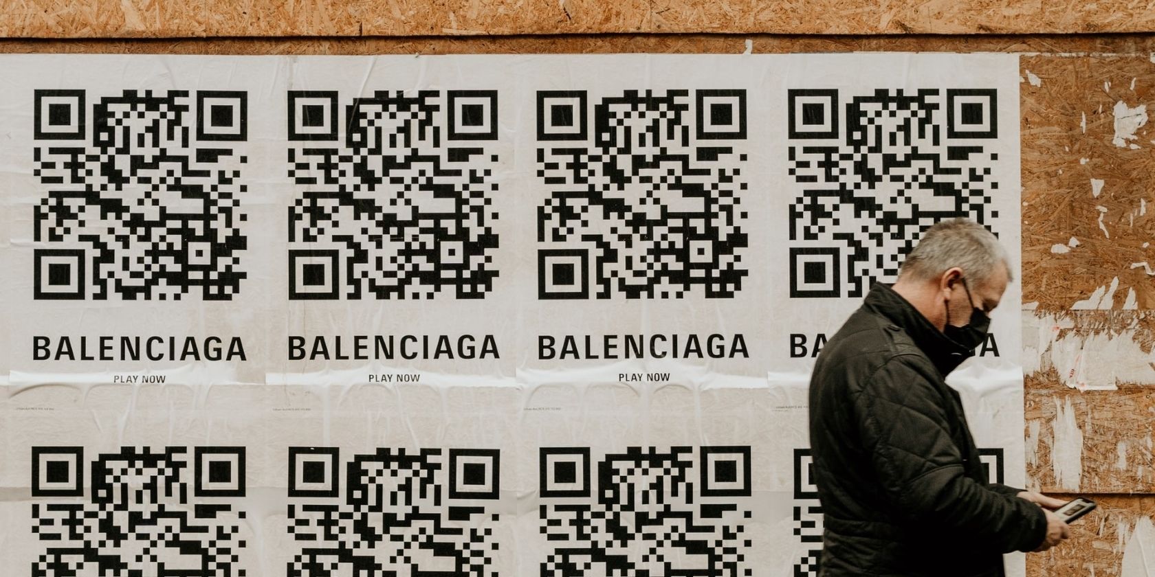 QR codes on wall and a man walking with phone in his hand
