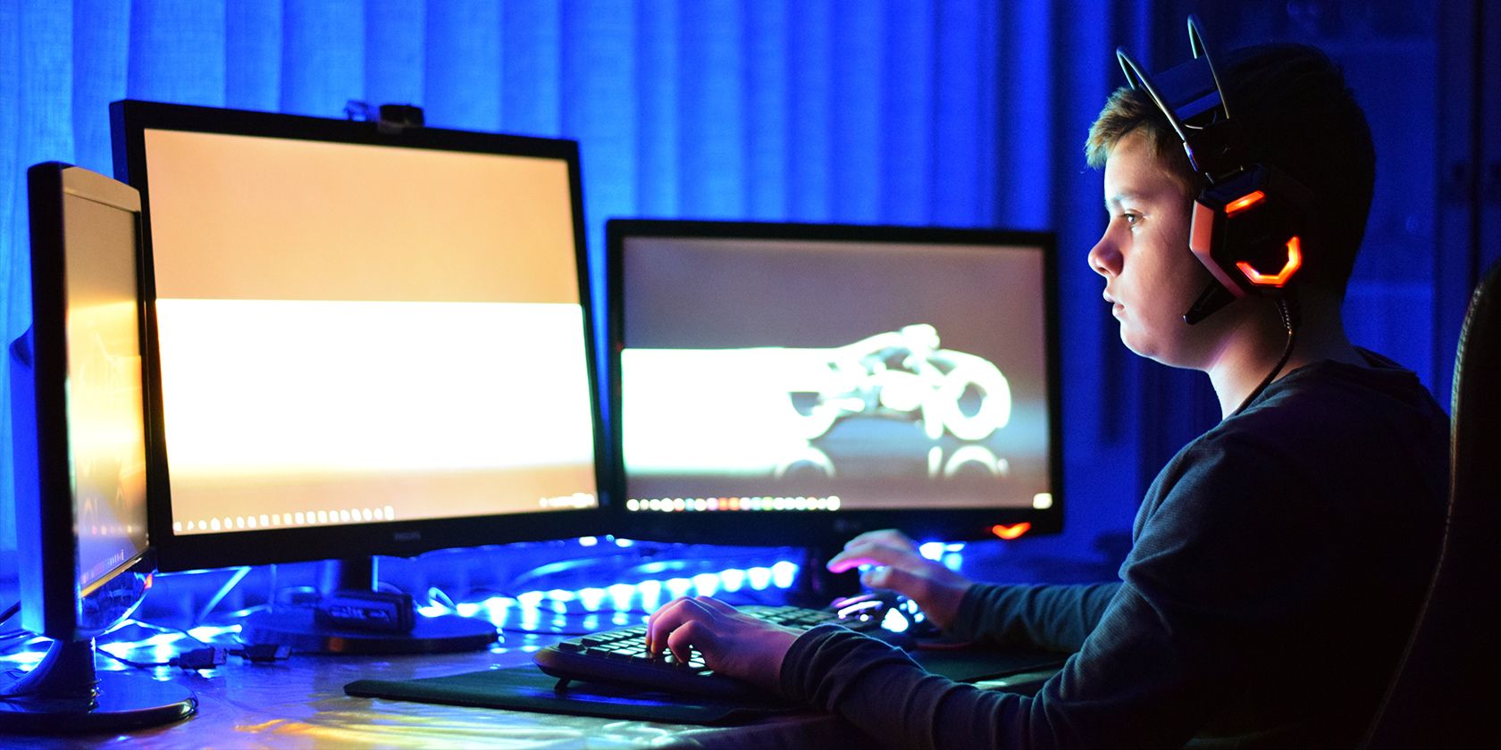 a kid playing a game in front of multi-monitor gaming PC