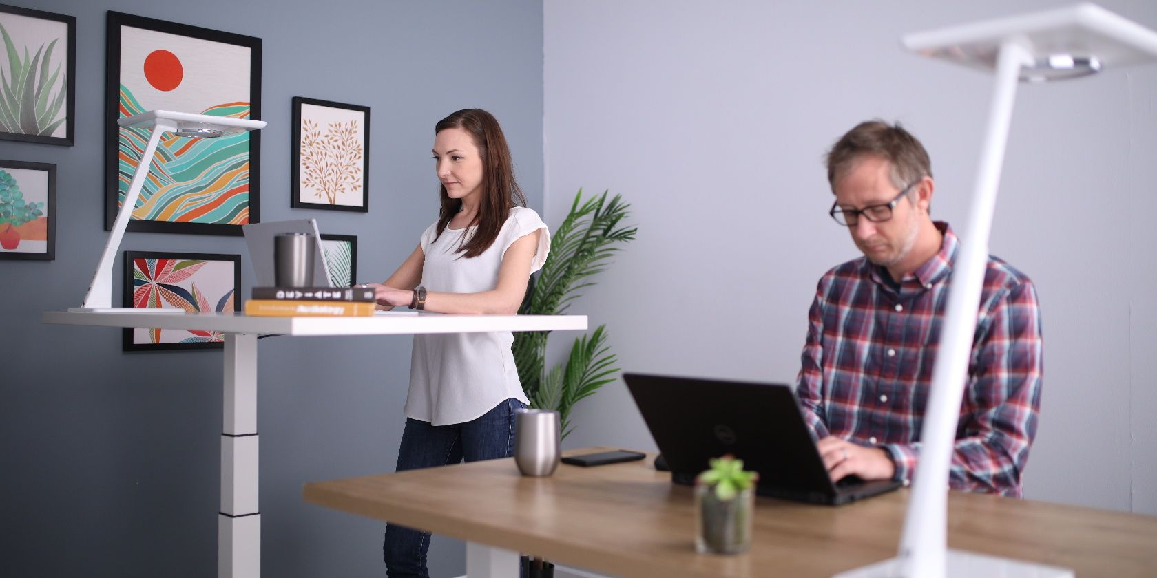 a woman and a man standing at their desks while they work