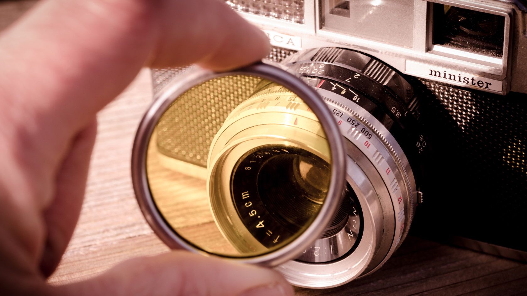 Person holding yellow colored camera lens filter in front of camera