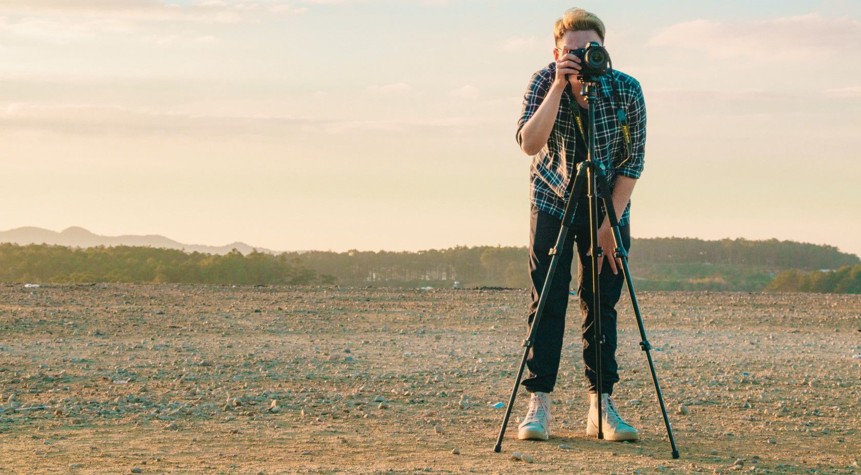 person standing in desert using camera tripod and taking a photograph