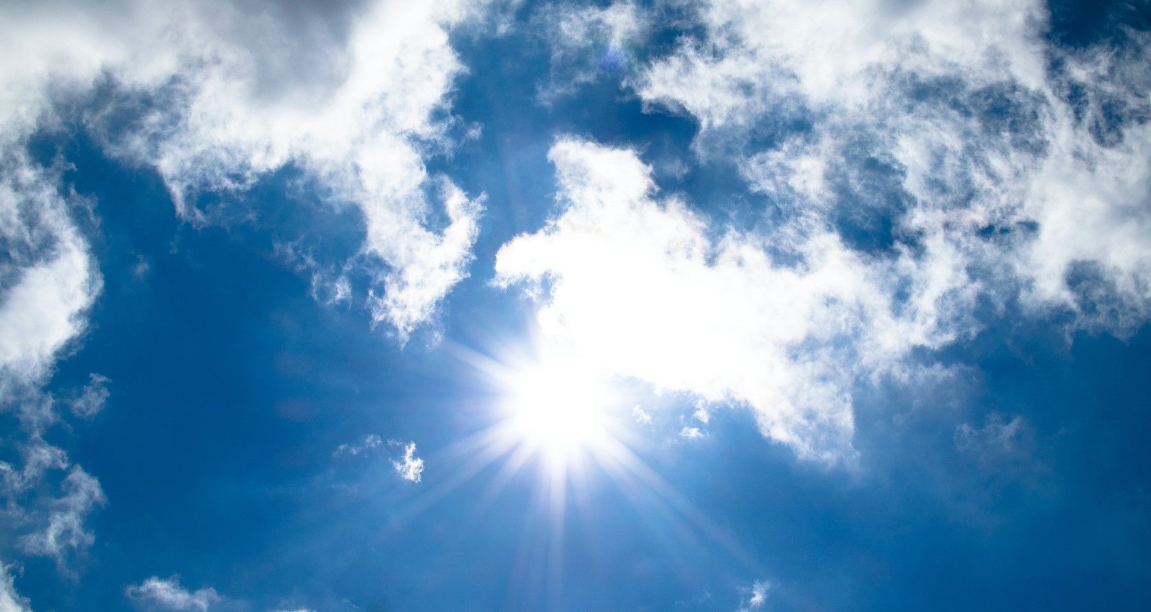 Bright sunlight shining through clouds with blue sky