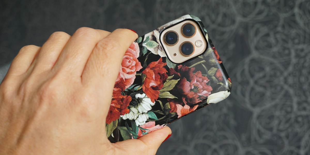 a woman's hand holding an iphone with a floral case